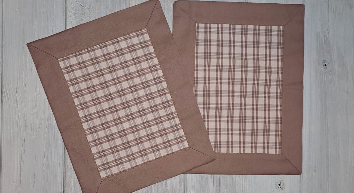 Tovagliette in stile country, nelle tonalità nocciola e bianco, fondo tinta unita nocciola, interno a fantasia quadretti. Angoli a cappuccio