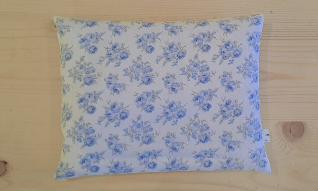 Cuscino rettangolare con noccioli di ciliegia, federa esterna con roselline azzurre su fondo bianco