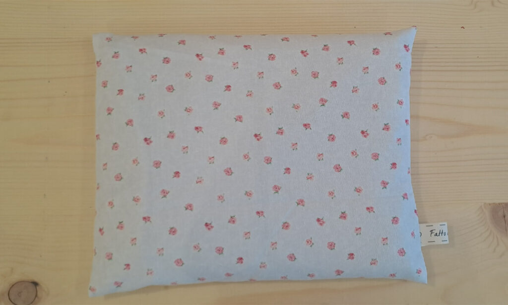Cuscino rettangolare con noccioli di ciliegia, con federa esterna fondo bianco sporco con roselline piccole rosa