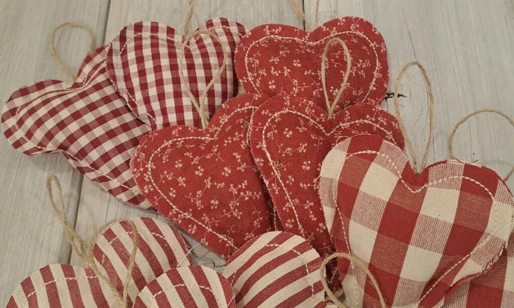 Cuori raggruppati per fantasia, nel dettaglio cuori con fiorellini ecrù su fondo rosso